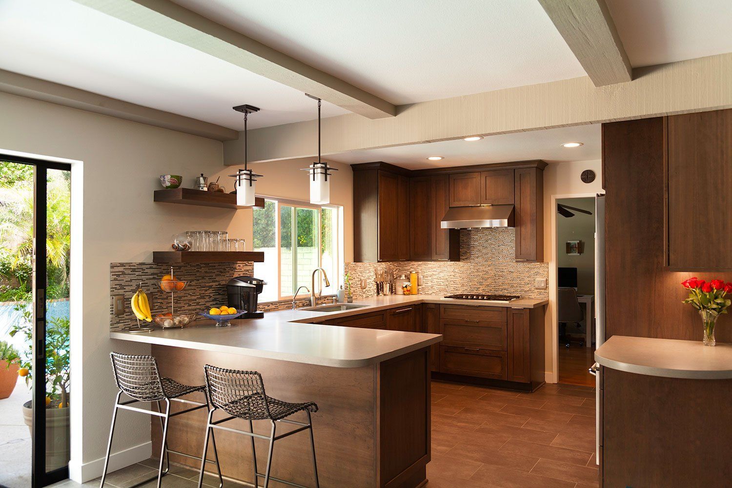 Modern kitchen with island seating, wood cabinetry, granite counters, and warm pendant lighting
