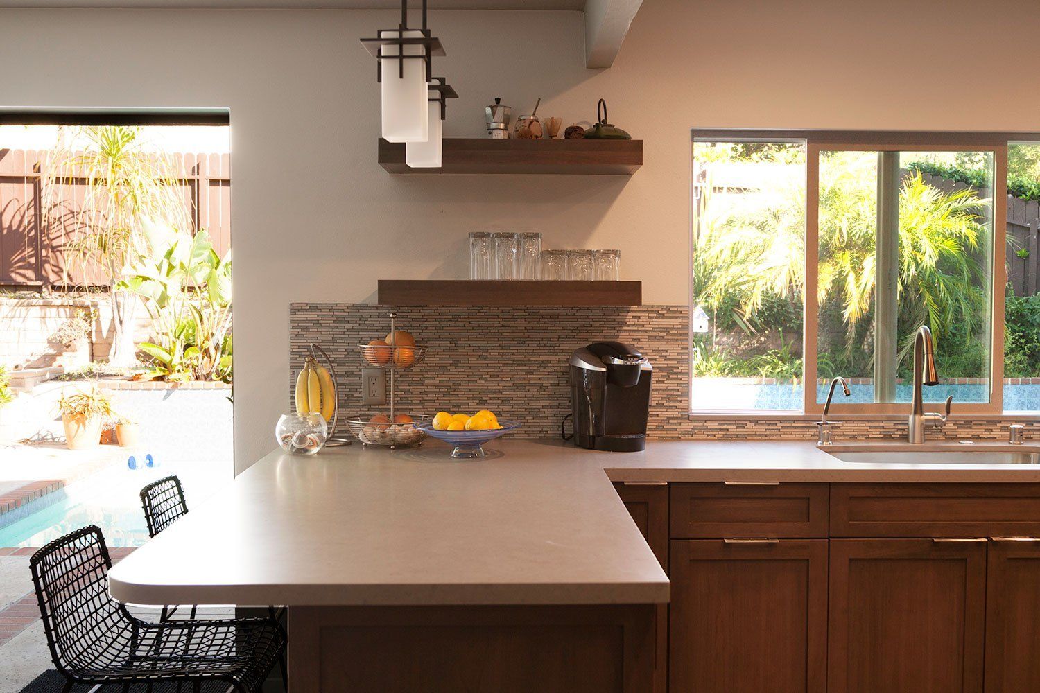 Bright kitchen with a stone backsplash, wooden cabinets, large window, and a central island with chairs
