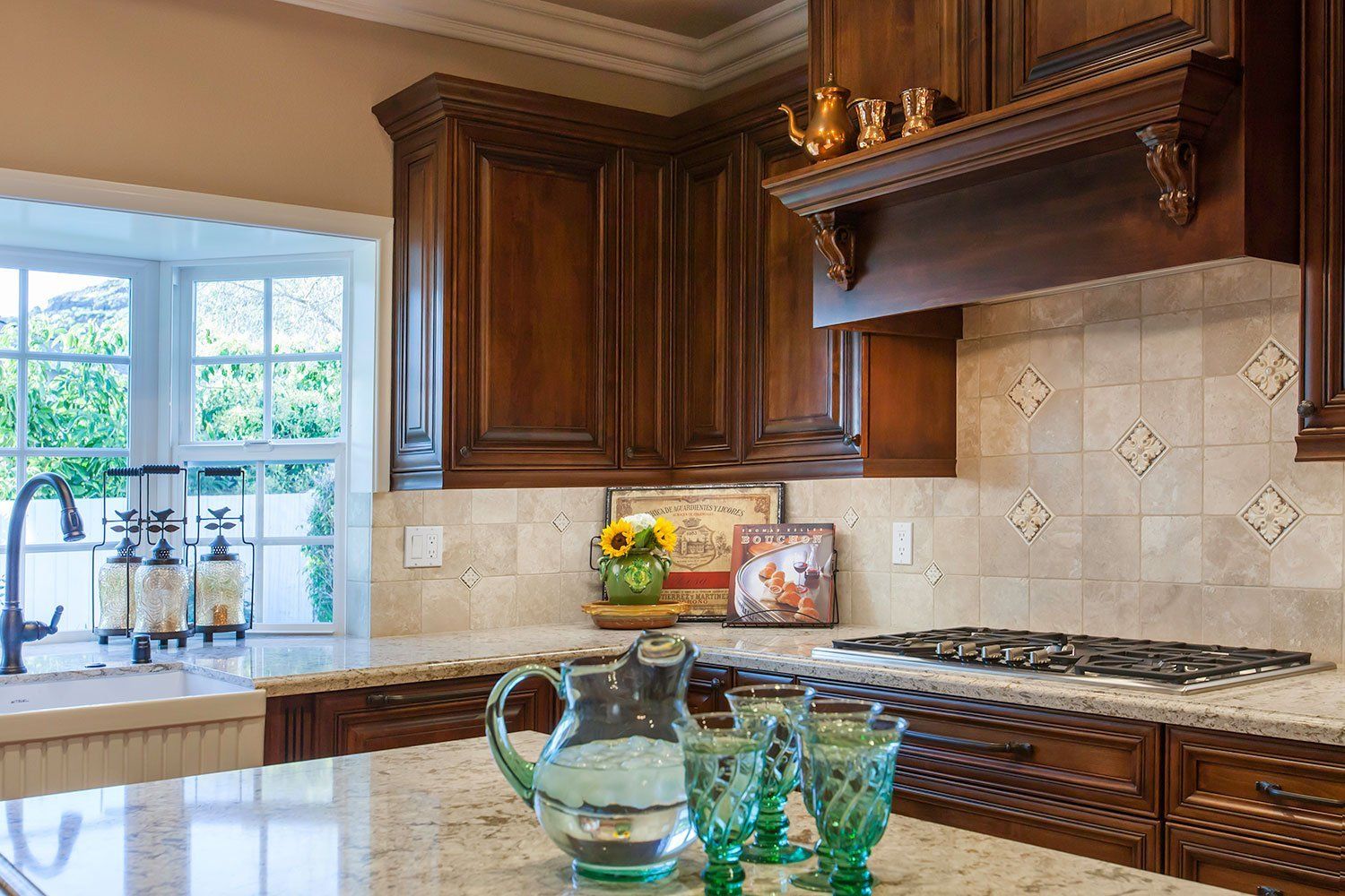 Elegant kitchen with dark wood cabinets, beige tile backsplash, and a sunlit window over the sink.