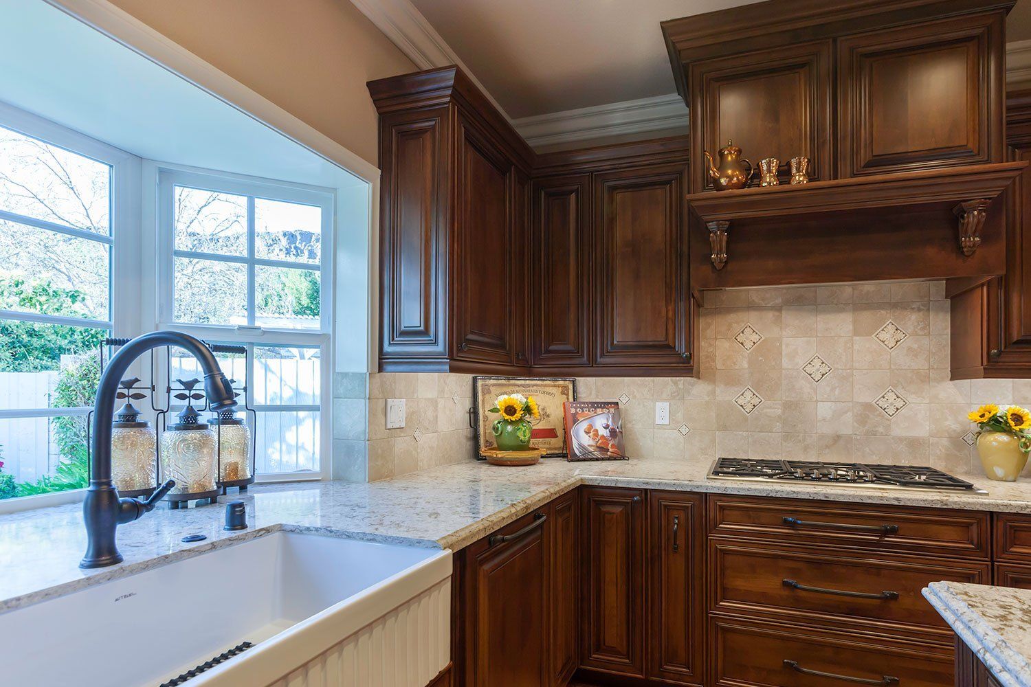 Kitchen corner with dark wood cabinets, stone backsplash, granite counters, and a sink by a window