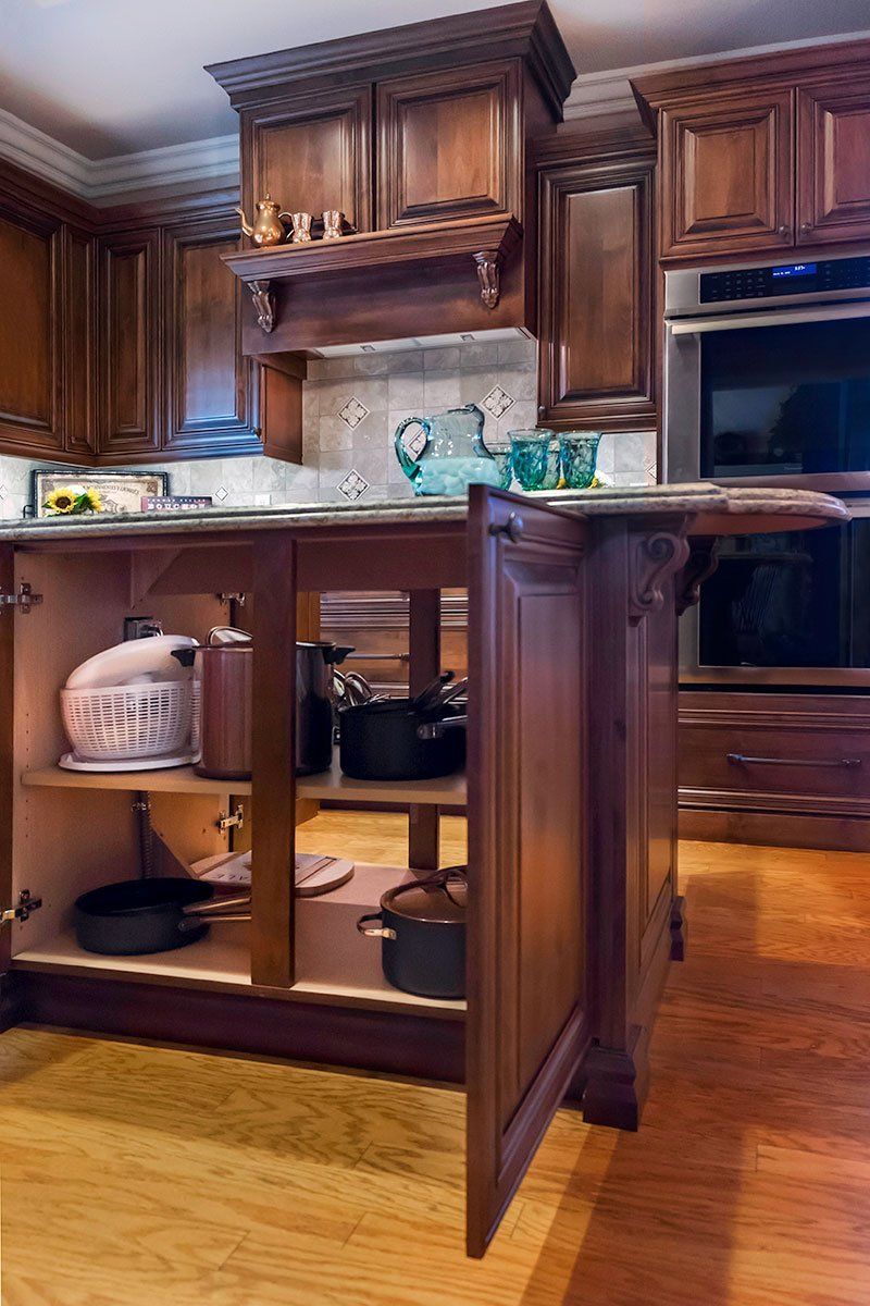 Kitchen island with open cabinet doors in a warm wood kitchen, revealing shelves and storage inside