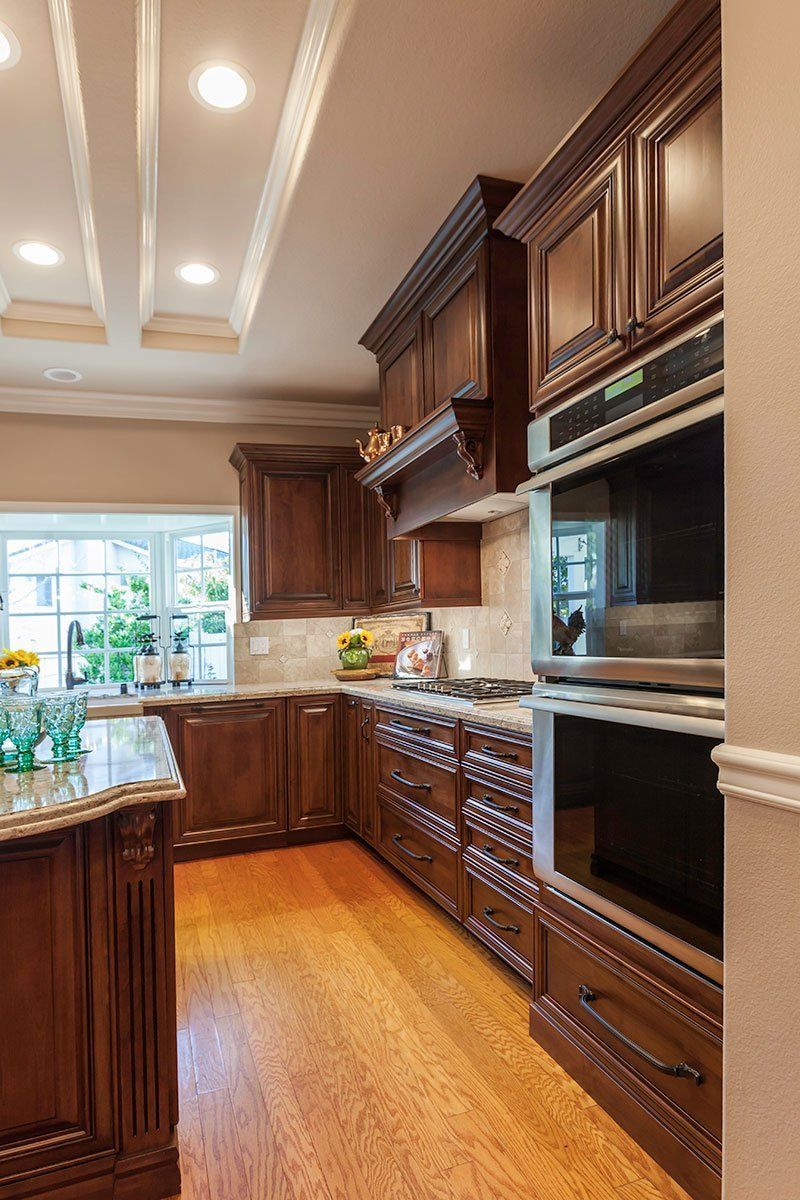 Luxurious kitchen with dark wood cabinets, stainless appliances, and a bright window over the sink.