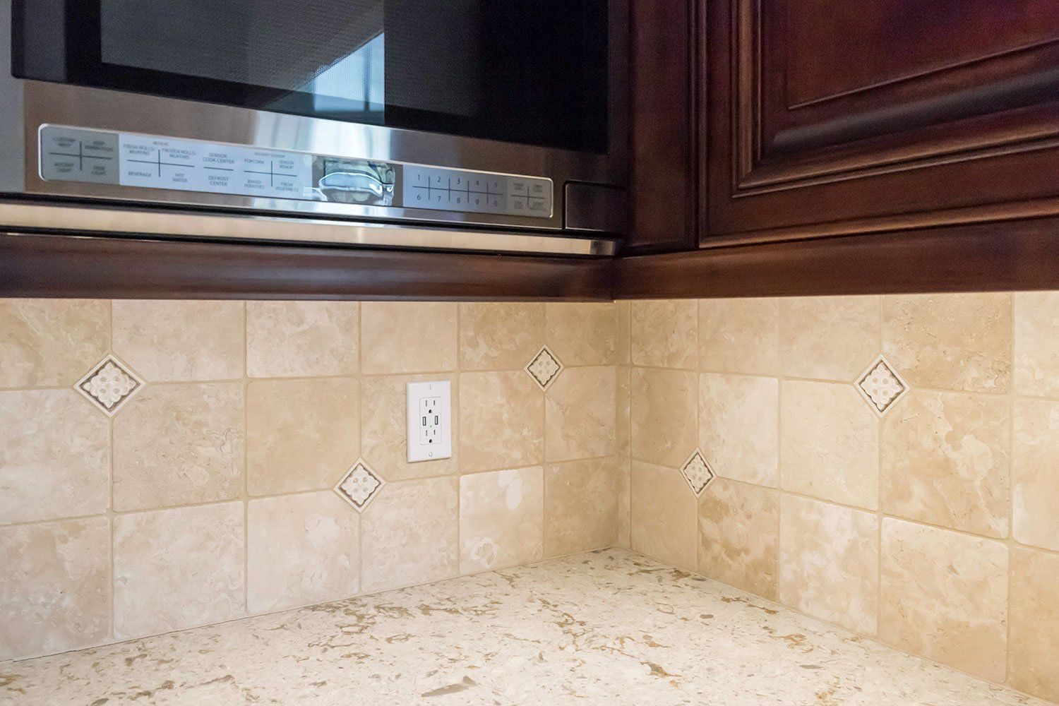 Kitchen countertop with beige tile backsplash, dark wood cabinets, and a window above the counter
