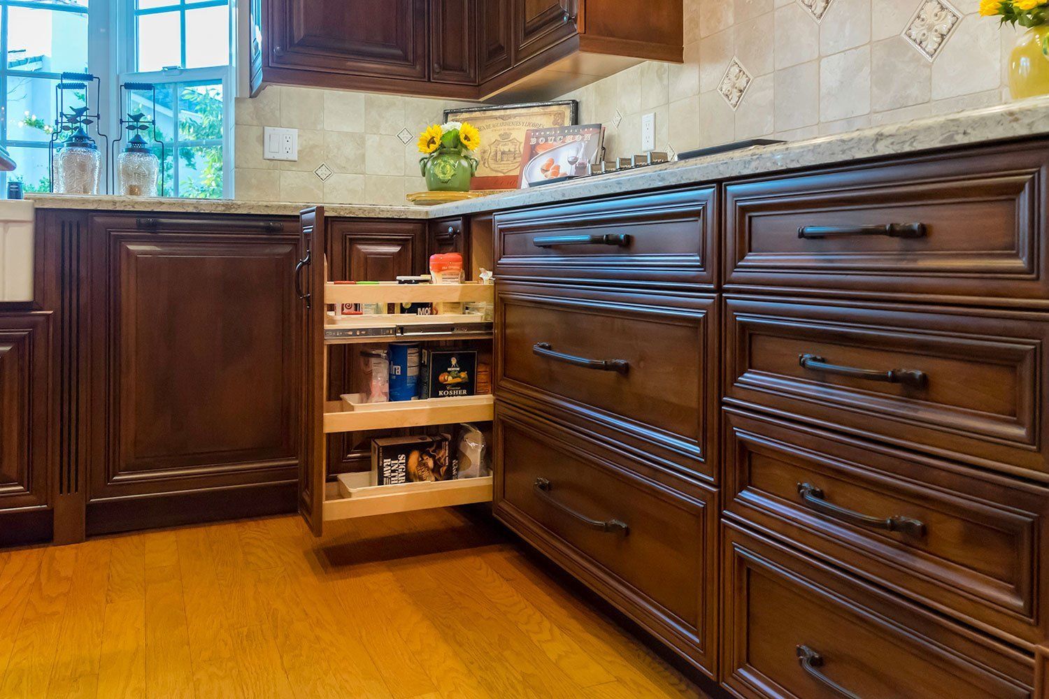 Kitchen with open pantry drawers beside dark wood cabinets and a tiled backsplash
