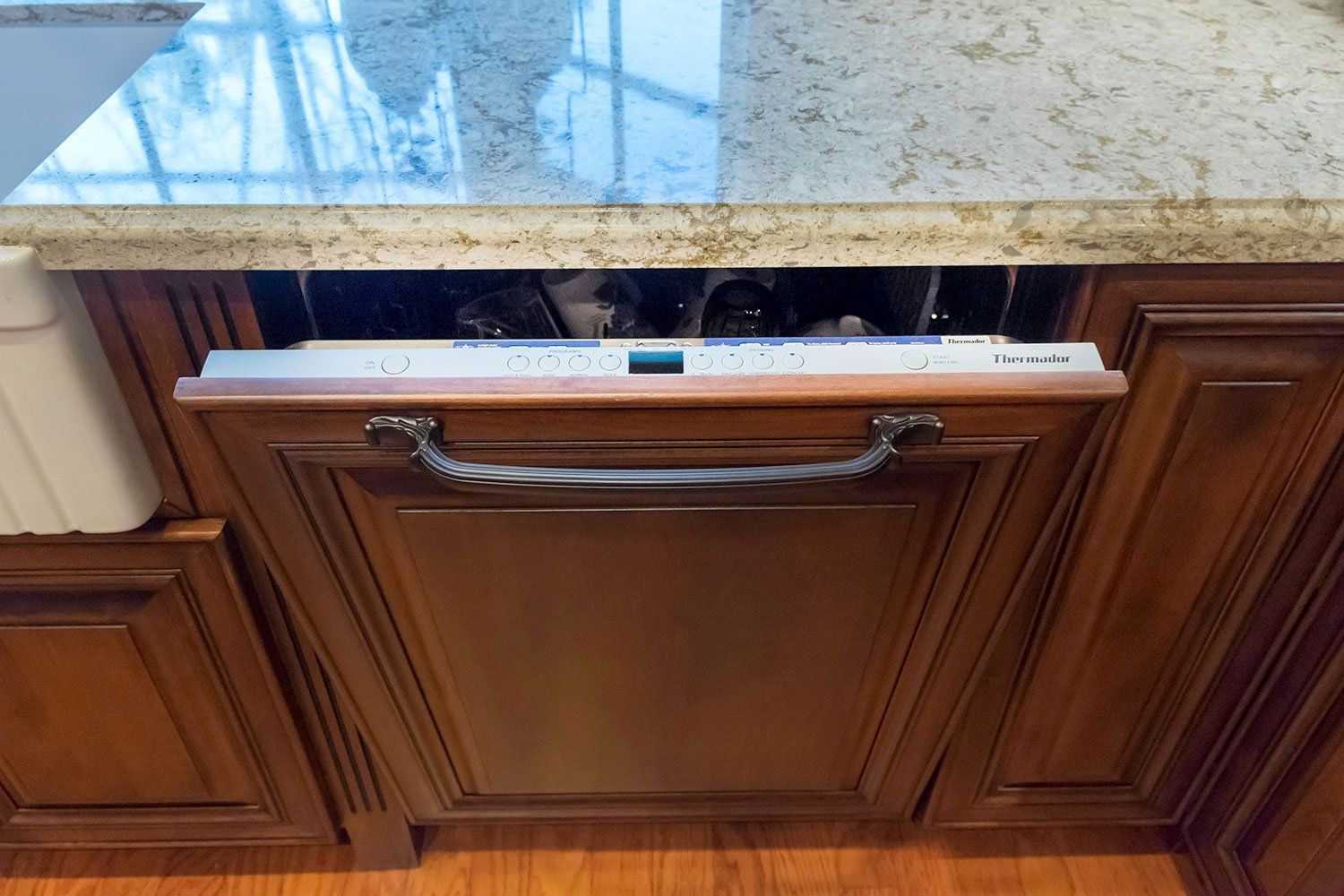 Partially open kitchen cabinet drawer beneath a granite countertop, with a towel bar on the front.