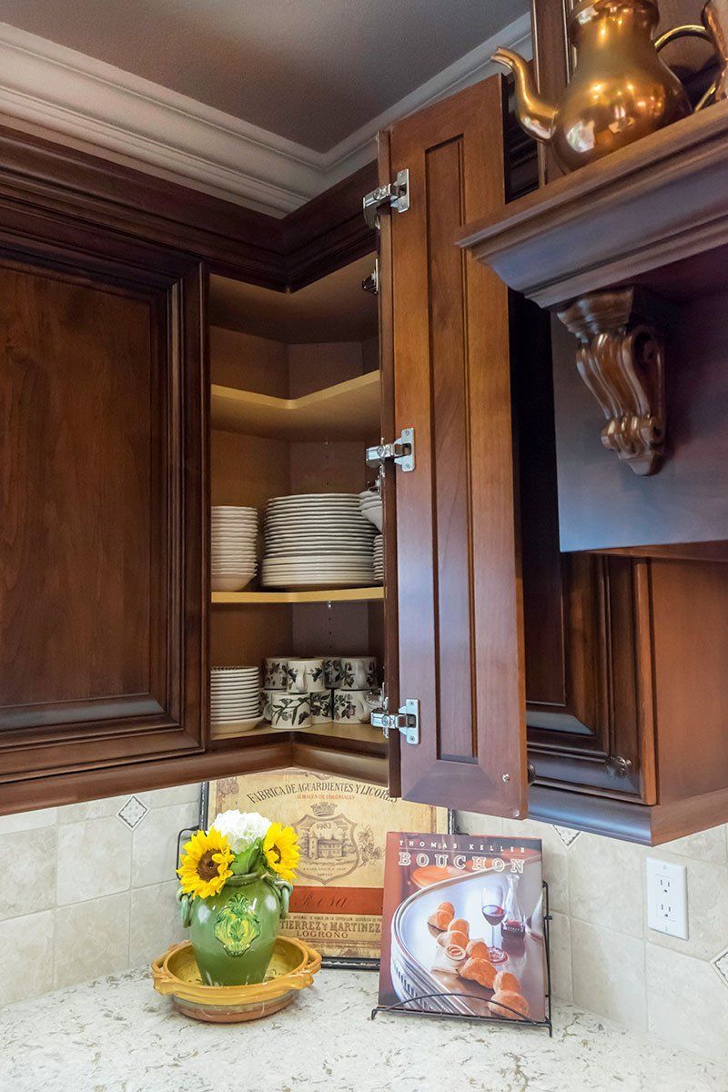 Dark wood kitchen cabinet with open shelves, white bowls, and sunflowers on a countertop