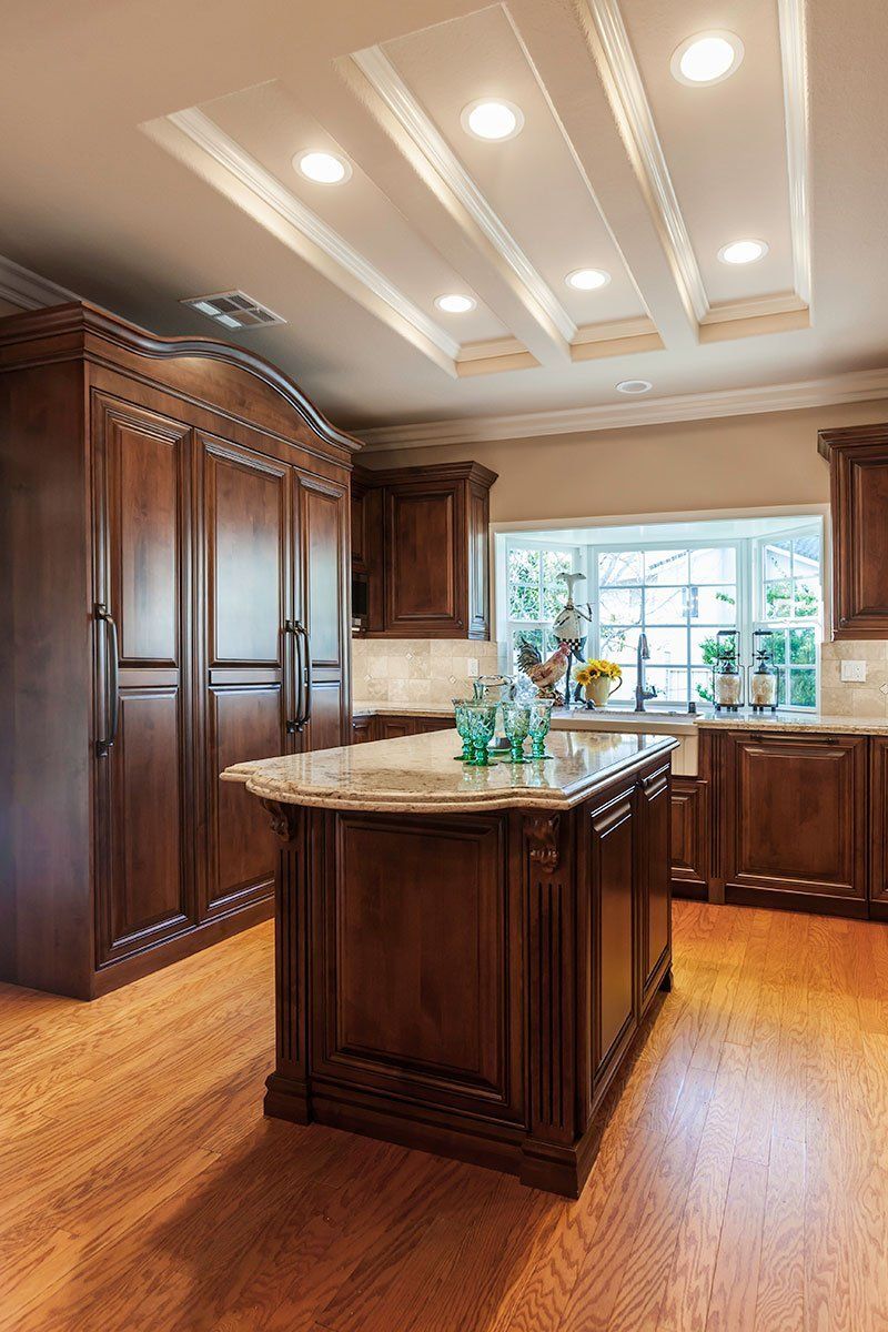 Spacious kitchen with dark wood cabinets, granite island, and bright recessed ceiling lights
