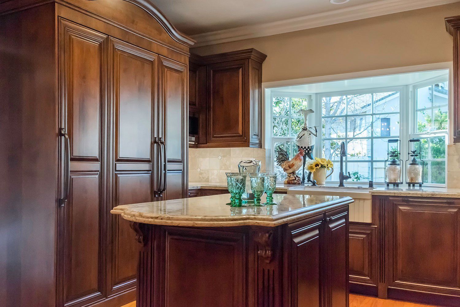 Luxurious kitchen with dark wood cabinets, granite island, and sunlit window over the sink.