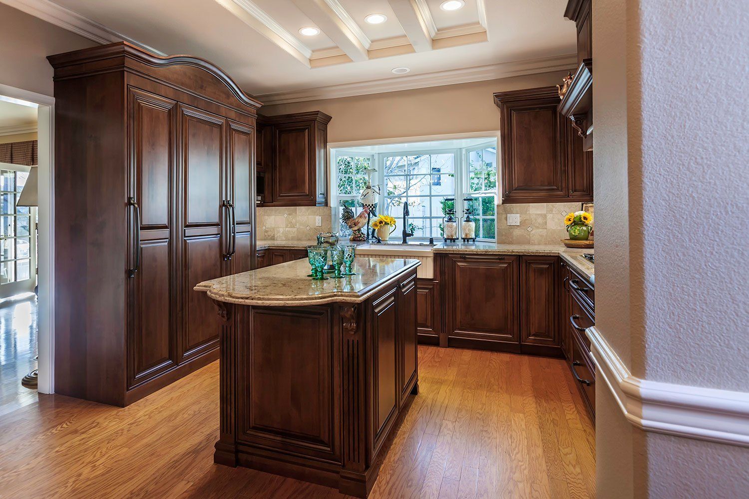 Elegant kitchen with dark wood cabinets, central island, and large window overlooking greenery