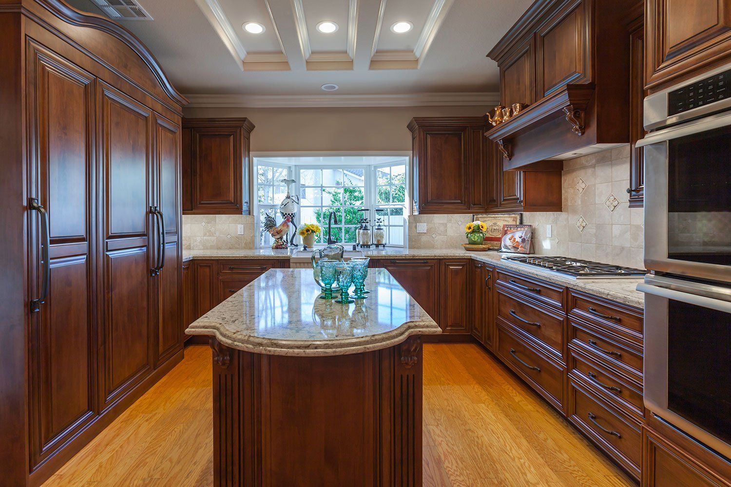 Luxurious kitchen with dark wood cabinets, granite island, and bright window over the sink