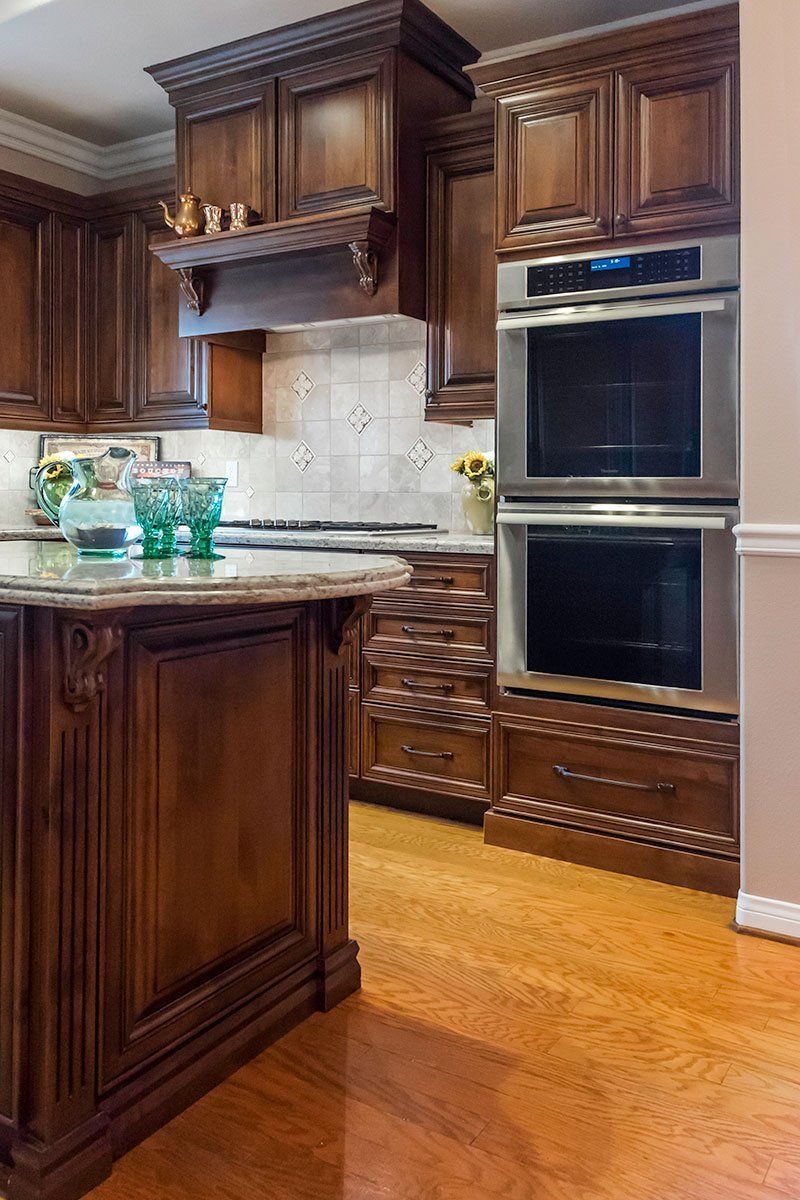 Dark wood kitchen with double ovens, marble countertops, and a hardwood floor.