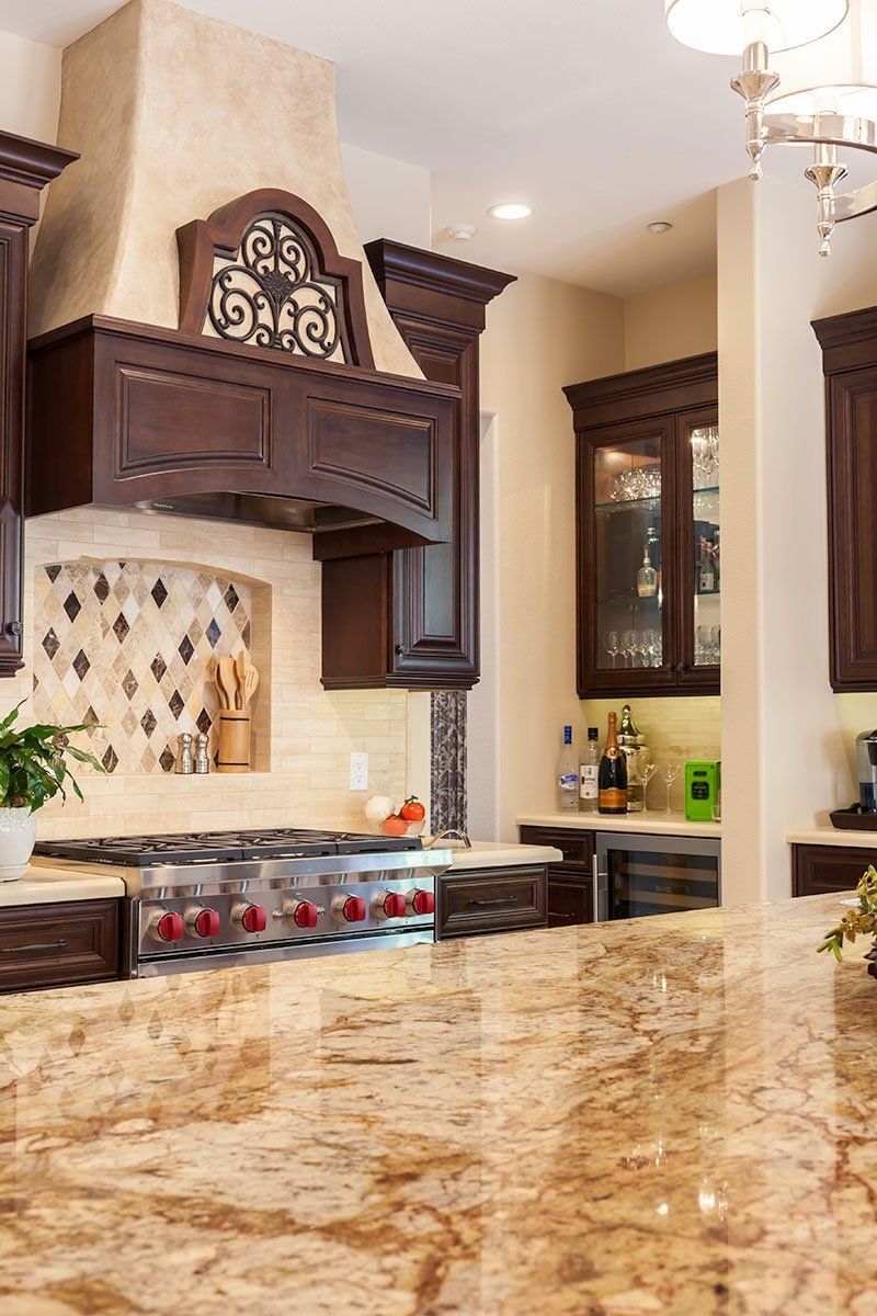 Elegant kitchen with dark wood cabinets, beige stone countertop, and decorative range hood