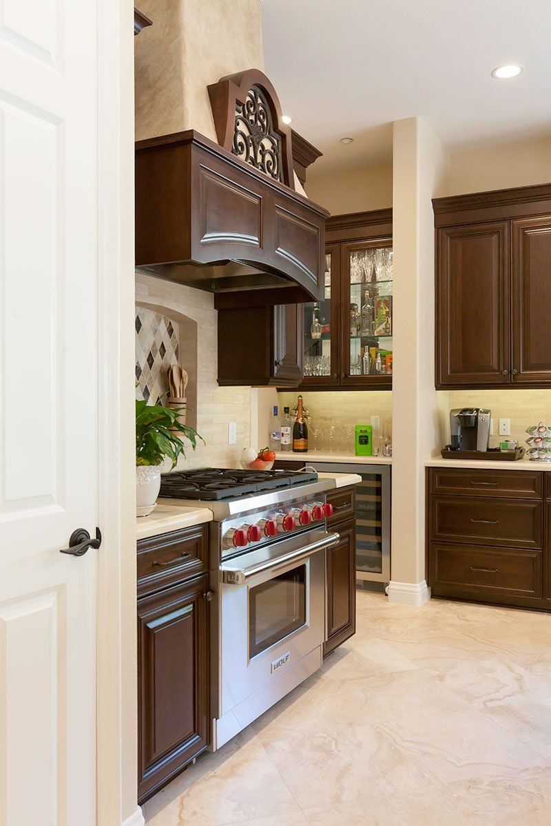 Modern kitchen with dark wood cabinets, stainless steel stove, and beige tile floor