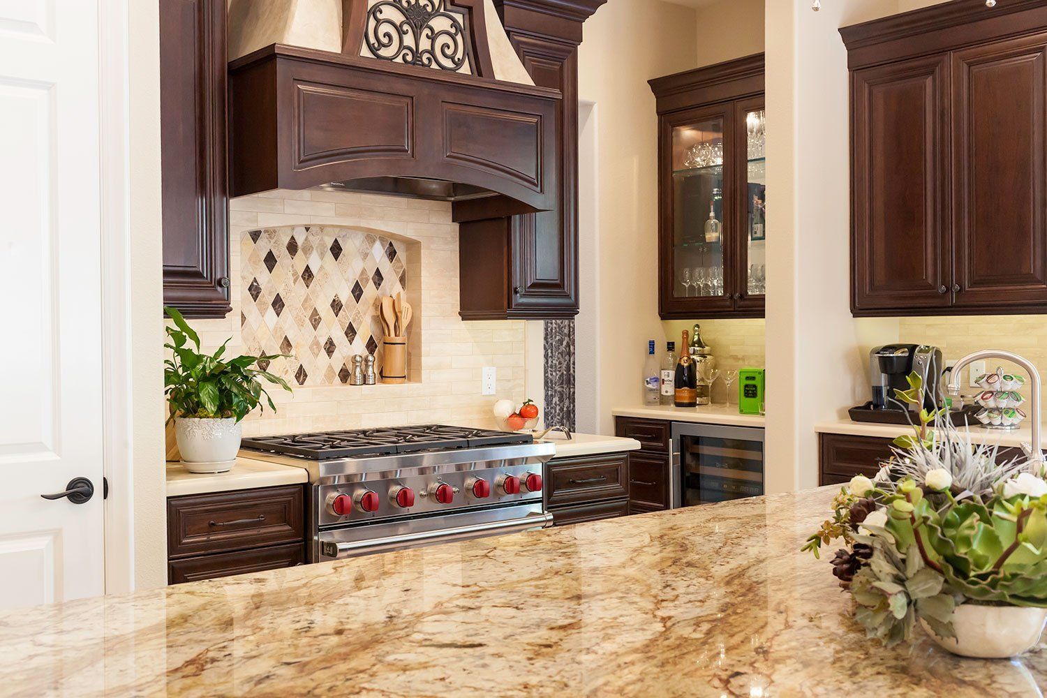 Modern kitchen with granite island, dark wood cabinets, stainless range, and floral centerpiece