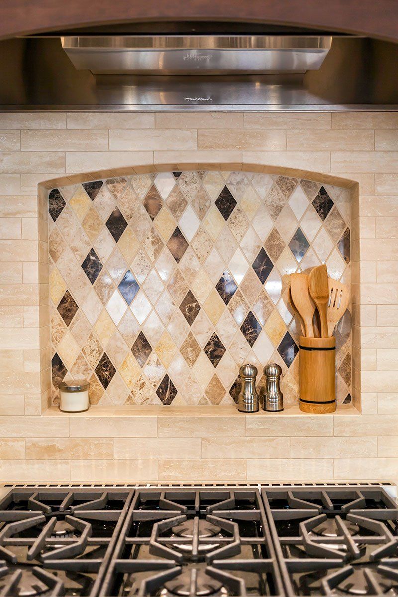 Kitchen backsplash with diamond mosaic tiles, utensil holder, and gas stove grate below