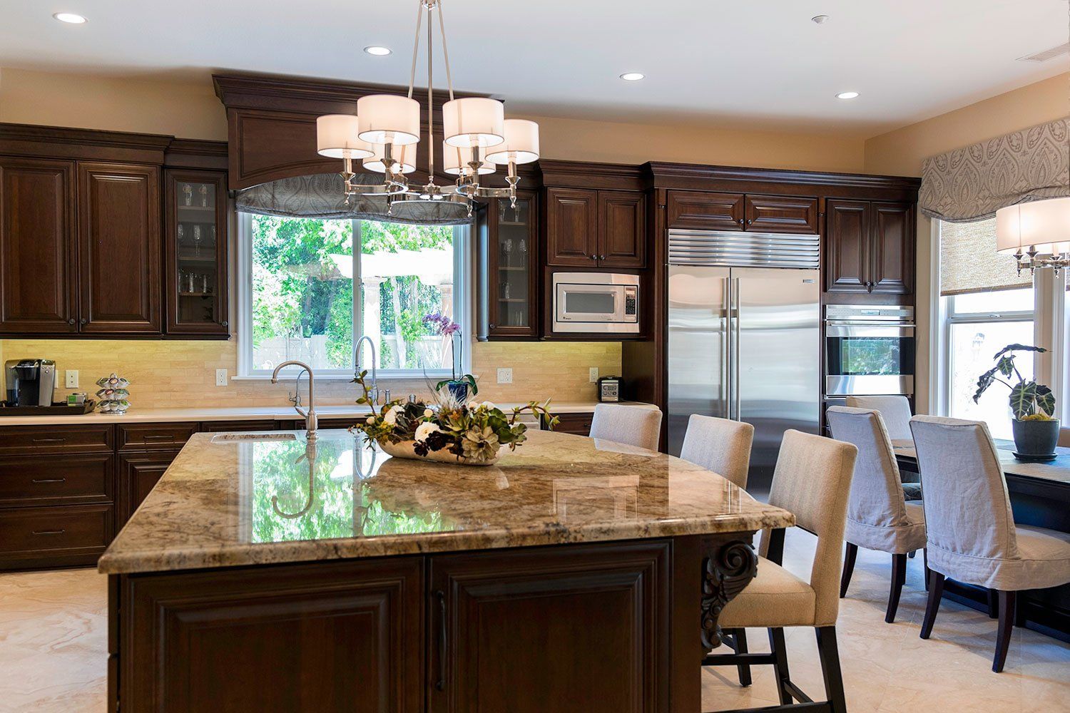 Modern kitchen with dark wood cabinets, granite island, pendant light, and breakfast nook by large window