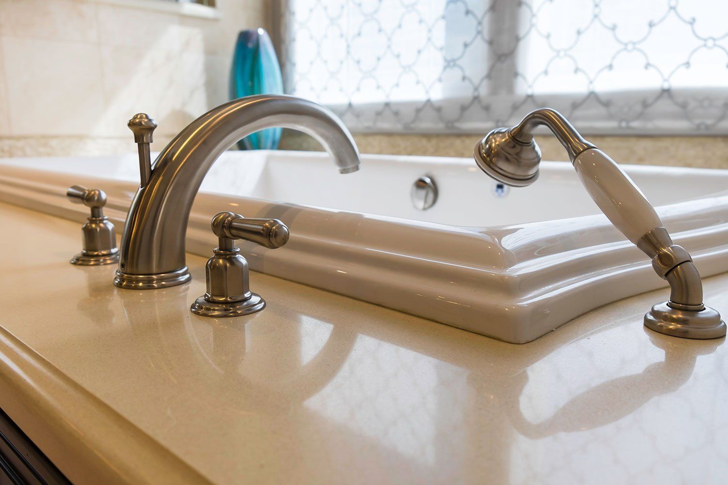 Bathroom sink with chrome faucet, soap dish, and cream-colored countertop near a window.