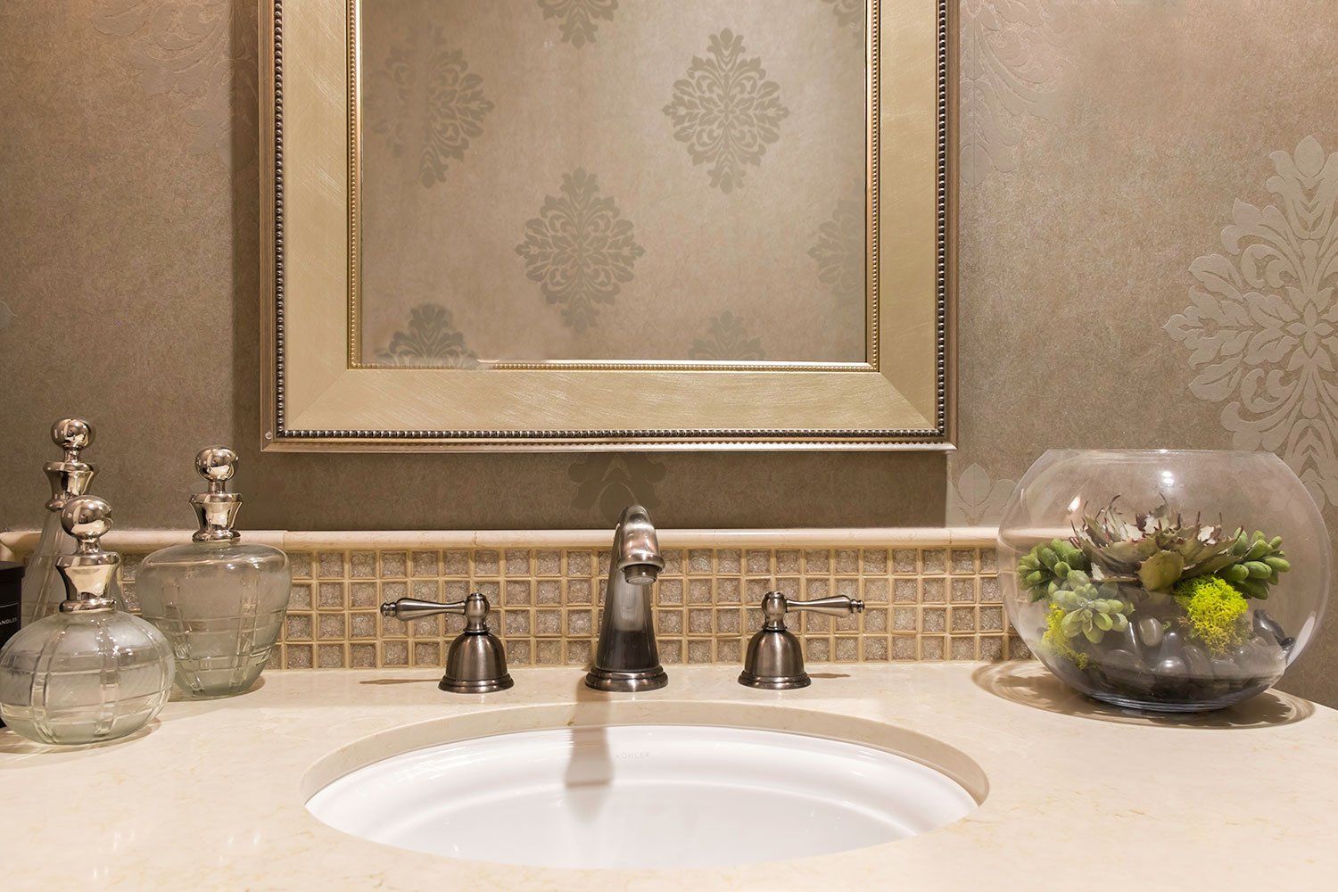 Elegant bathroom vanity with double sink, mirrors, and decorative glass containers on the counter.