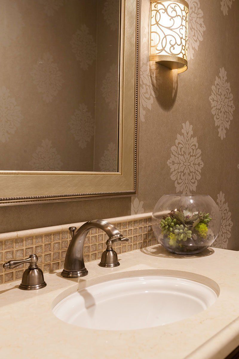 Elegant bathroom vanity with white sink, chrome faucet, marble countertop, and decorative wall sconce.