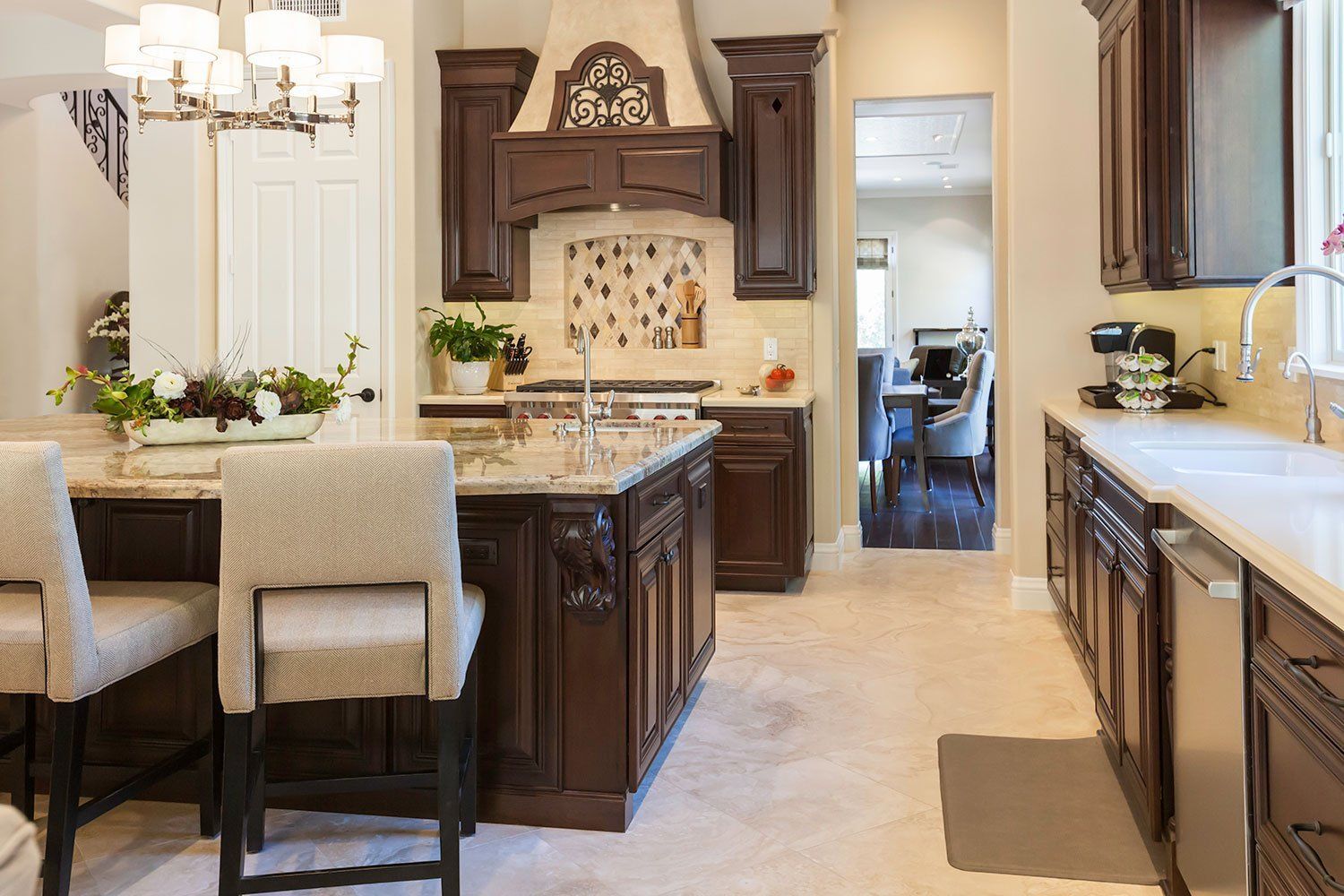 Elegant kitchen with dark wood cabinets, granite island, beige stools, and a doorway to an adjoining room