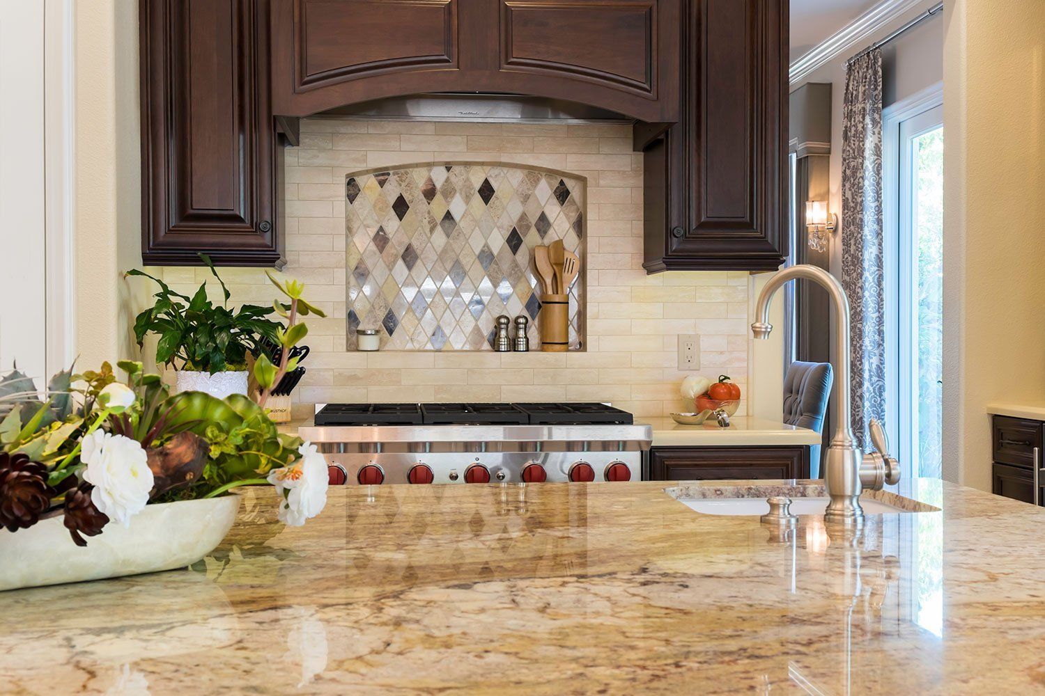 Luxury kitchen with granite island, dark wood cabinets, decorative backsplash, and bright window light