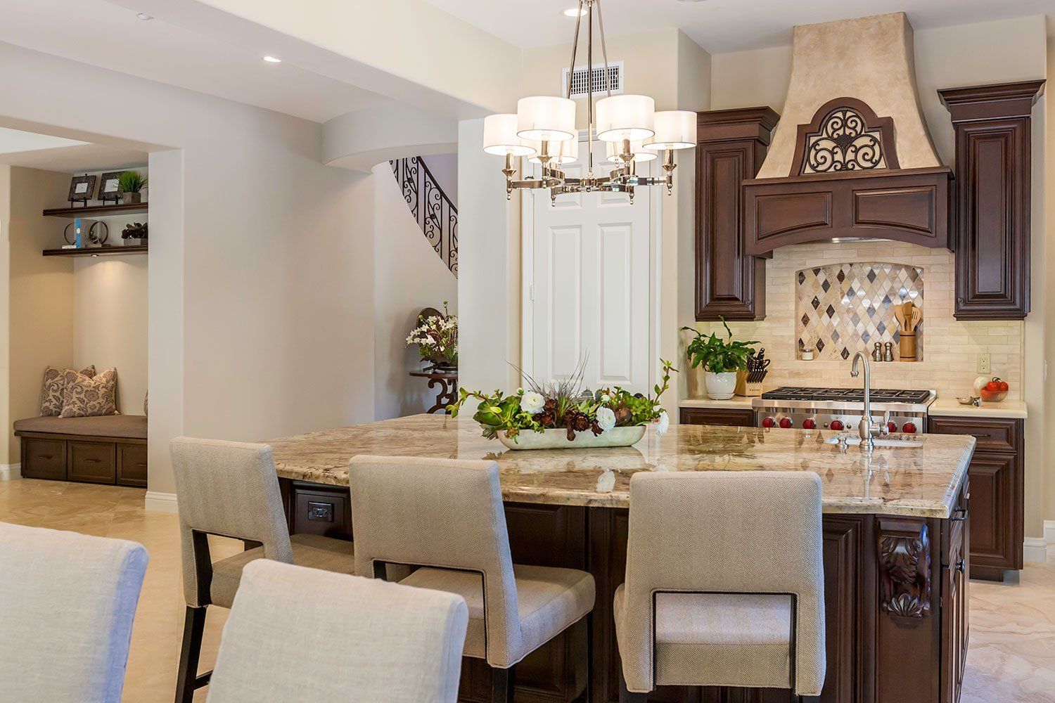 Elegant dining room with chandelier, dark wood table, upholstered chairs, and kitchen island in the background