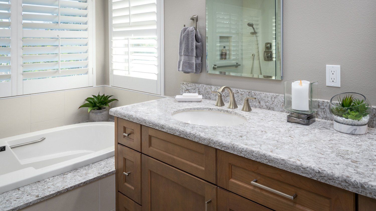Bright bathroom with double vanity, granite countertop, bathtub, and large window shutters