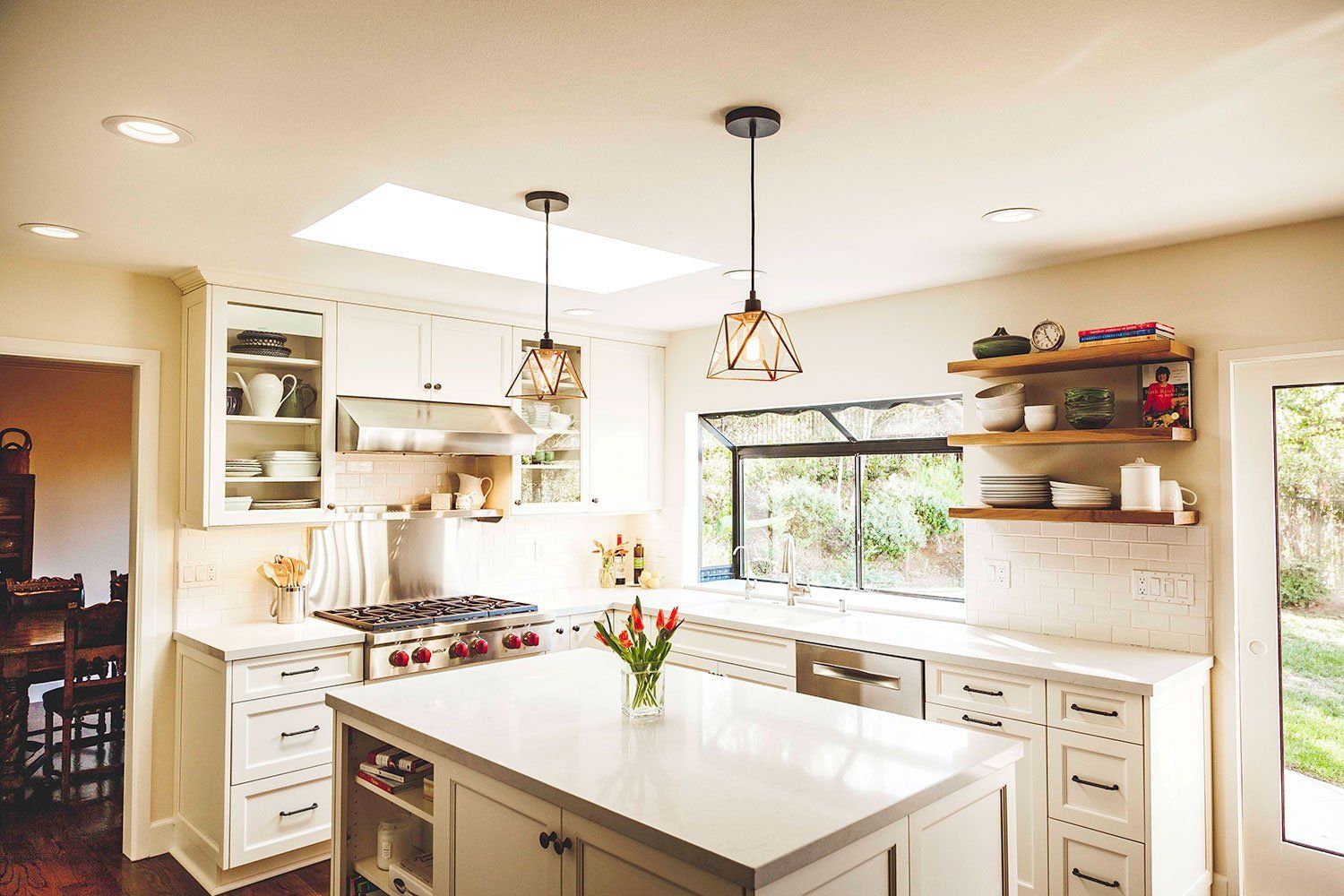 Bright modern kitchen with white cabinets, island, pendant lights, and a large window
