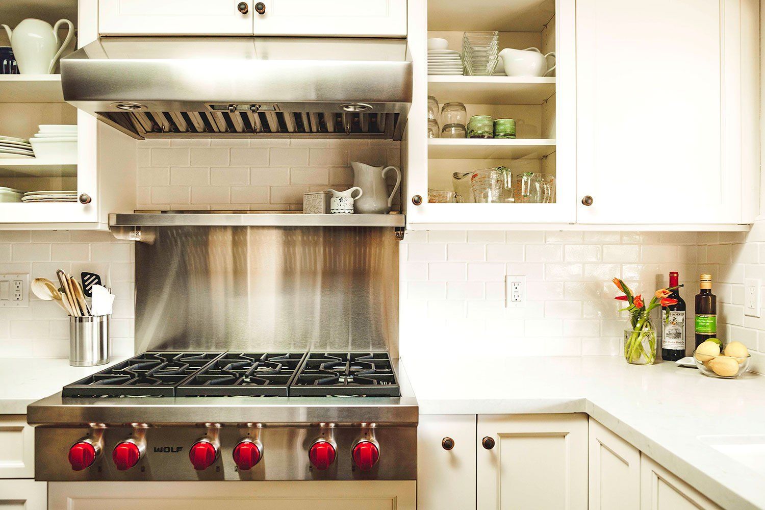 Modern kitchen with stainless steel range, white cabinets, and fruit on the counter