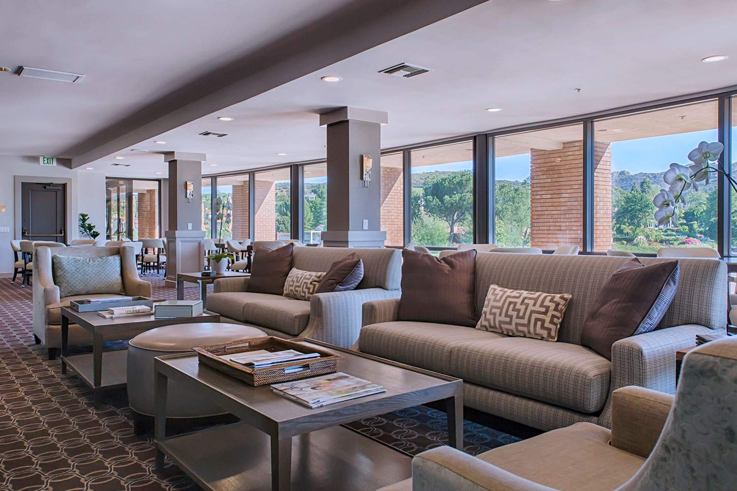 Bright modern lounge with sofas, coffee tables, and large windows overlooking mountains