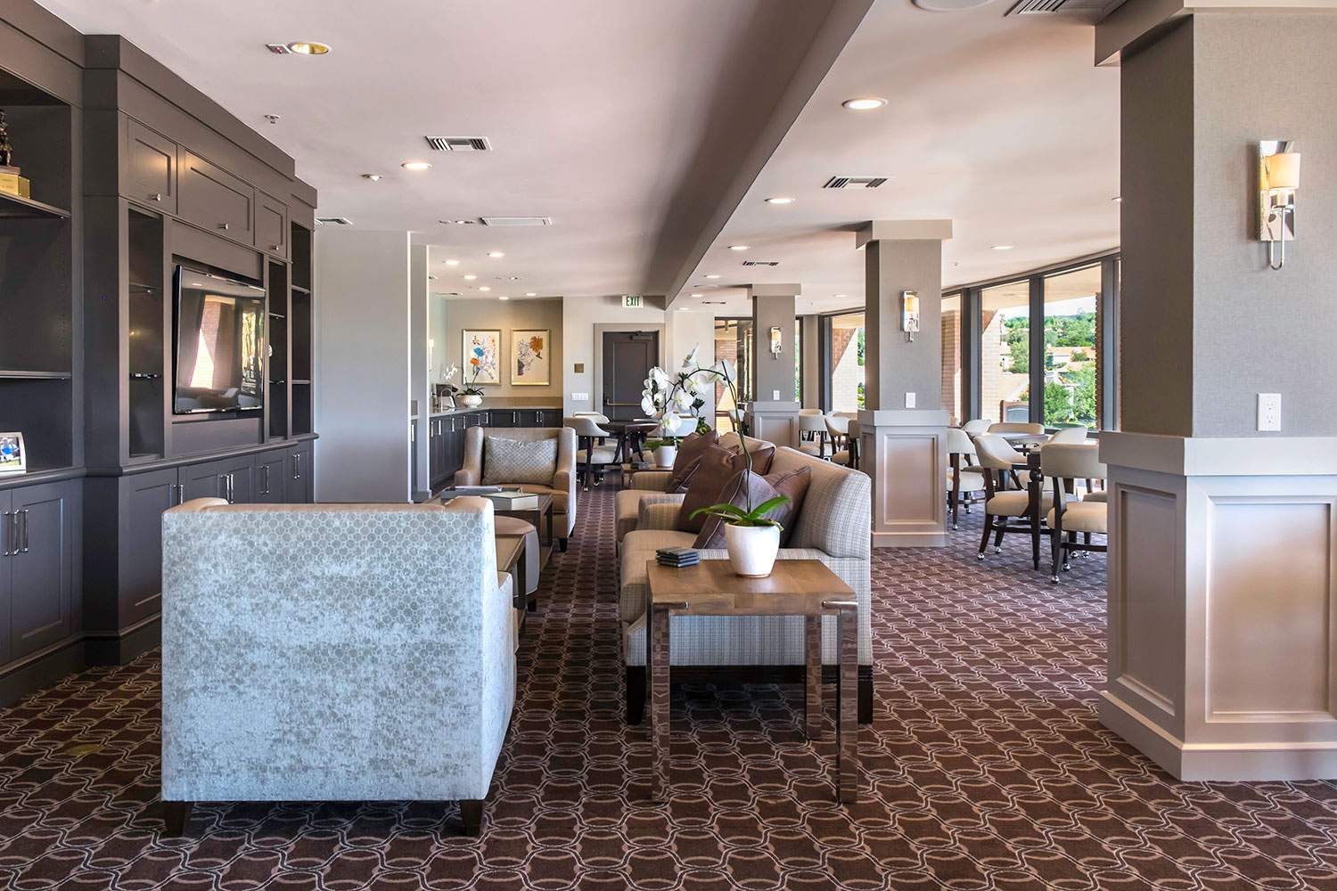 Elegant restaurant dining area with patterned carpet, upholstered chairs, and large windows