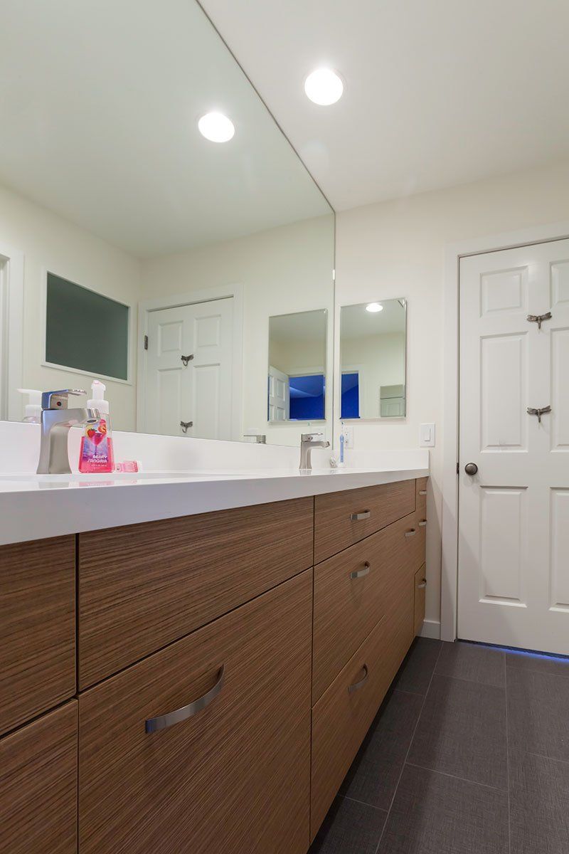Modern bathroom vanity with mirror, sink, white doors, and recessed ceiling lights