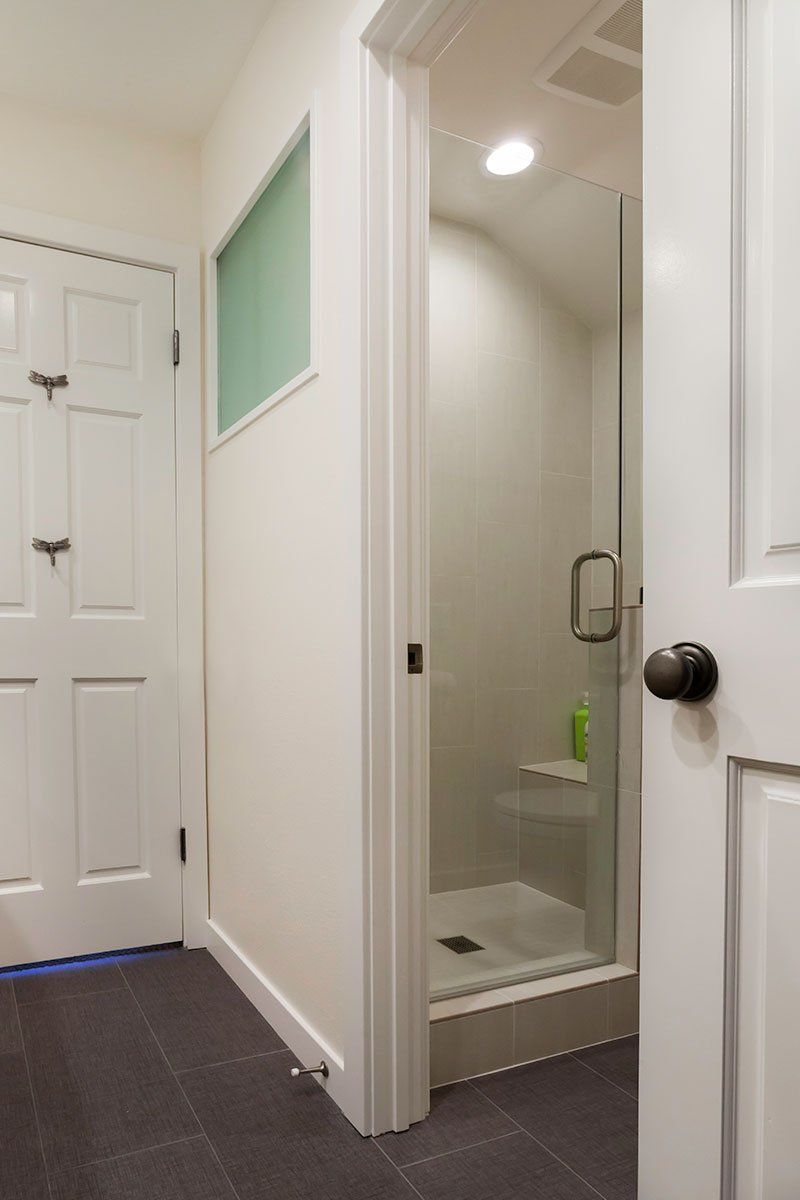 Hallway with open bathroom door, shower visible, and white paneled doors along the wall.