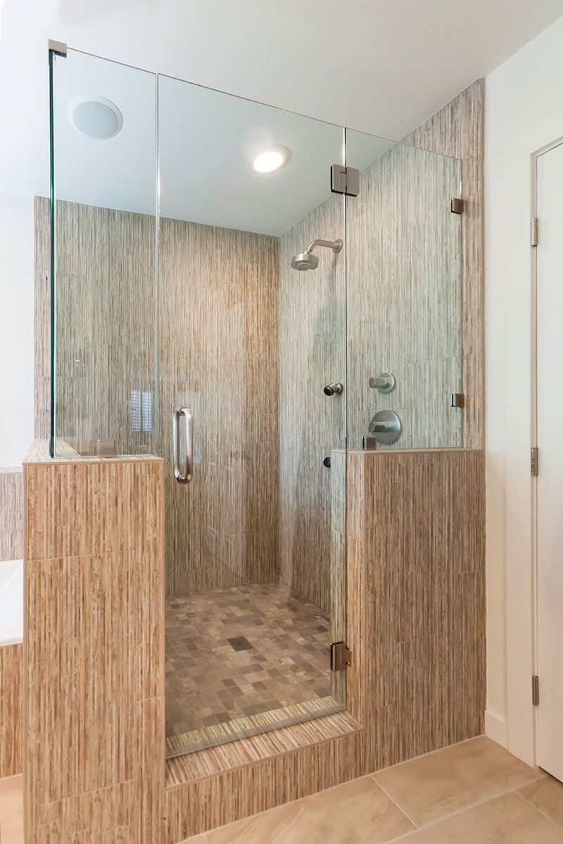 Modern bathroom shower with wood-look tile, glass enclosure, and a rainfall showerhead.