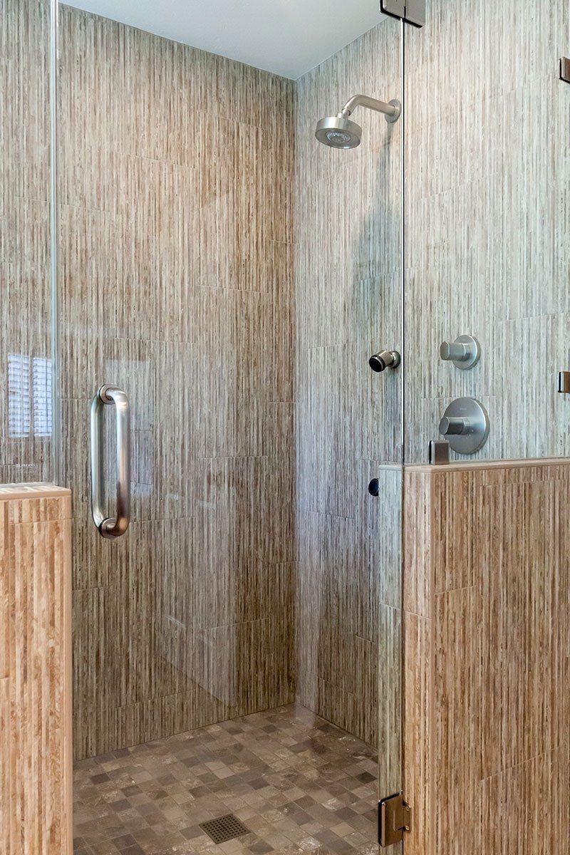 Modern shower stall with wood-grain walls, glass door, and chrome fixtures.