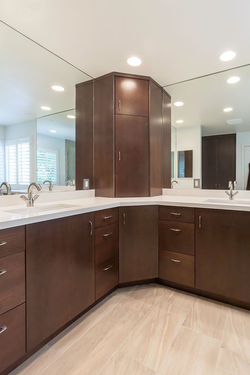 Modern bathroom with dark wood cabinets, white countertop, and large mirror.
