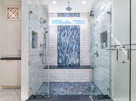 Modern glass shower with blue mosaic tile waterfall feature and rain showerheads