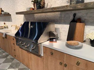 Modern kitchen with a stainless steel stove, wooden shelves, and plates on a white countertop