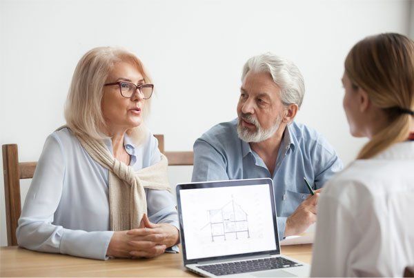 Three people in a meeting discussing a laptop at a table