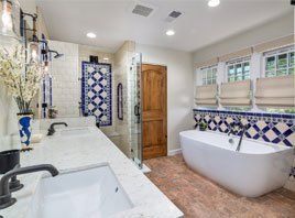 Bright bathroom with freestanding tub, double sink, blue tile accents, and walk-in shower។