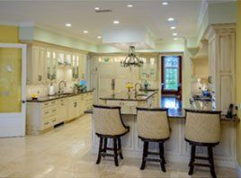 Bright luxury kitchen with cream cabinets, island seating, and recessed lighting