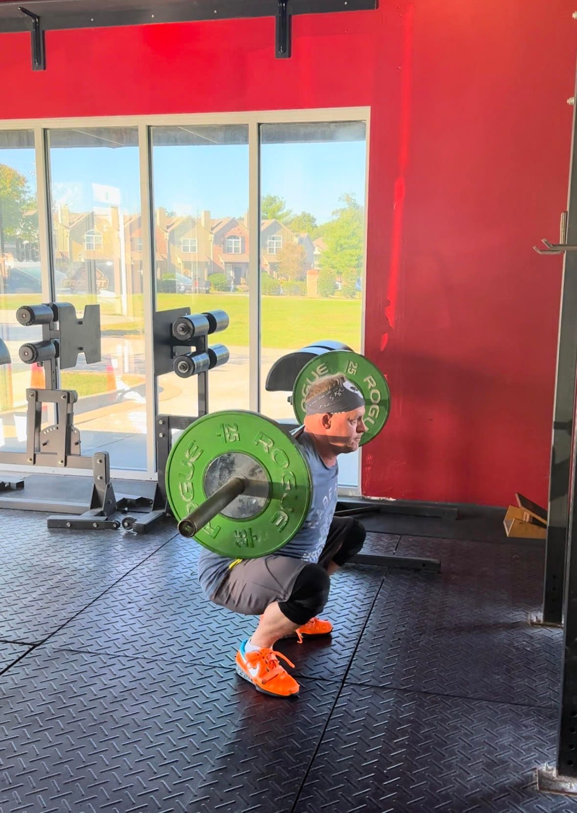 A man is squatting with a barbell in a gym.