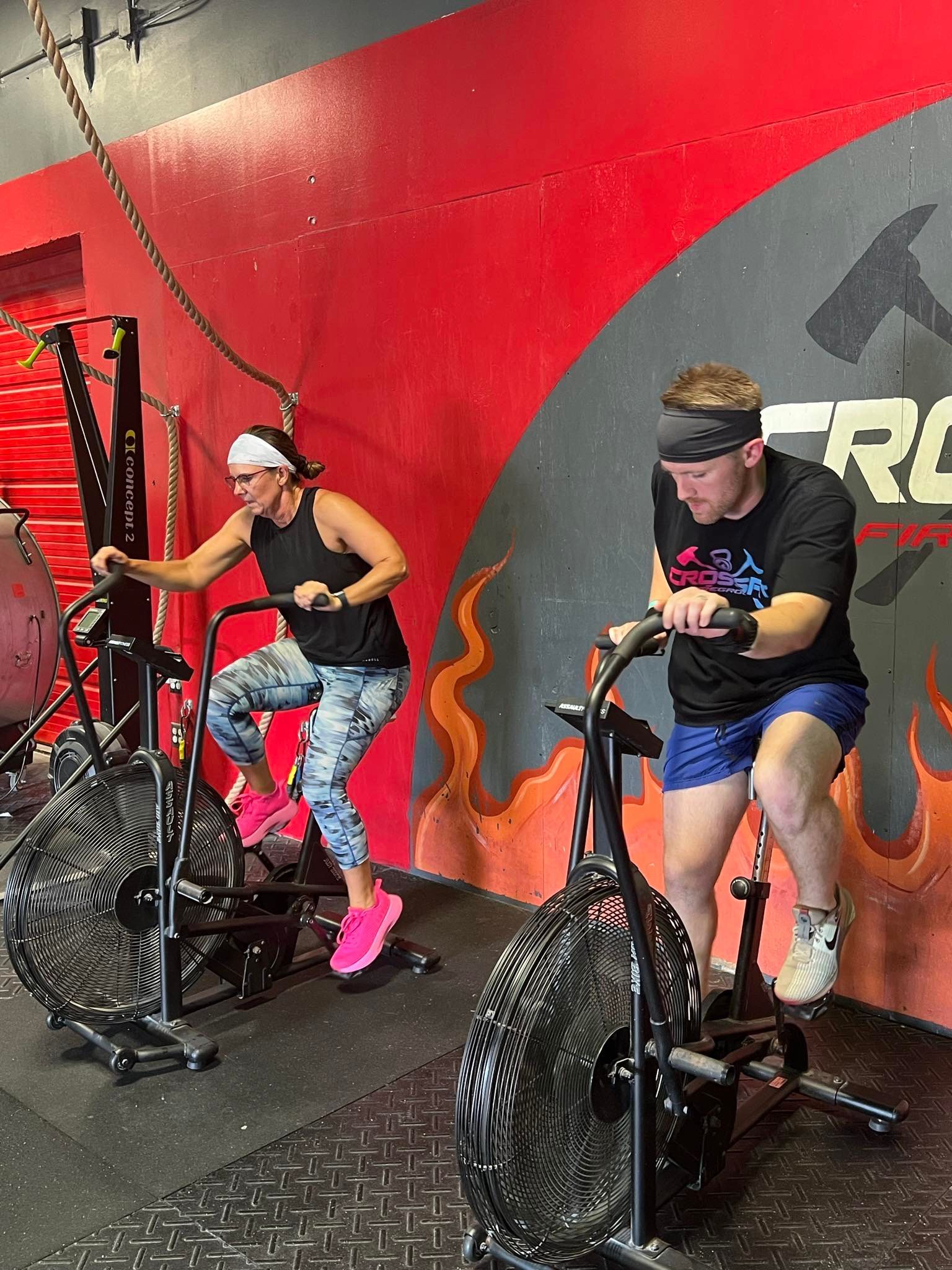 A man is squatting down with a barbell in a gym.
