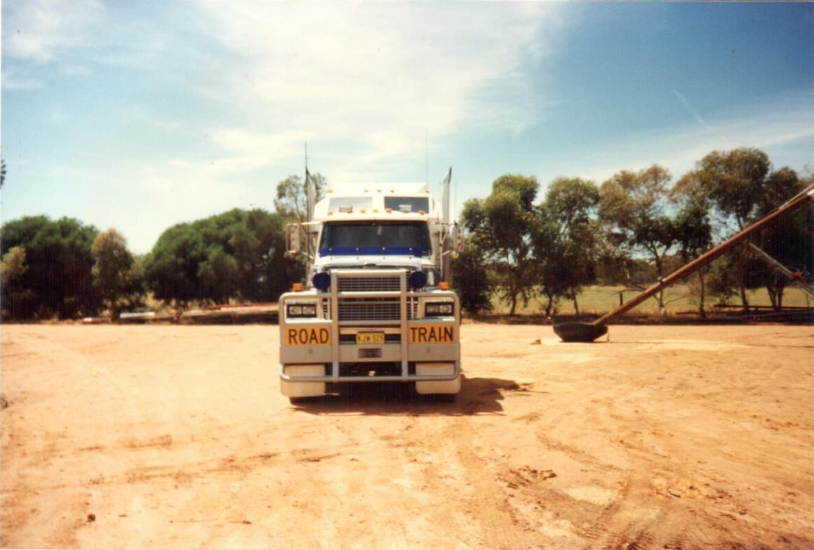 Semi-truck driving on an empty highway under a cloudy sky