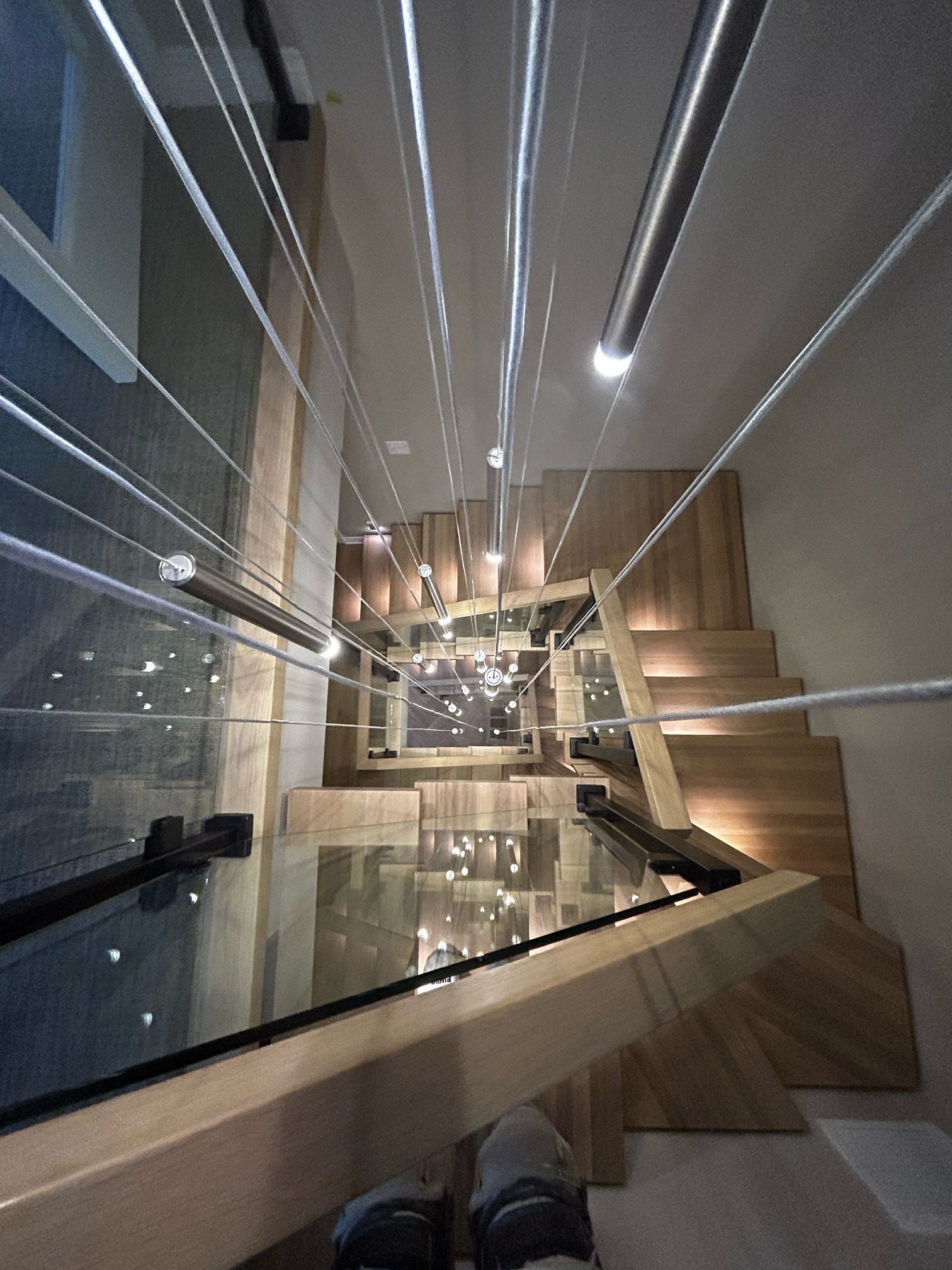 Escalier en verre moderne dans un intérieur minimaliste avec marches en bois, rampes en métal et éclairage réfléchissant