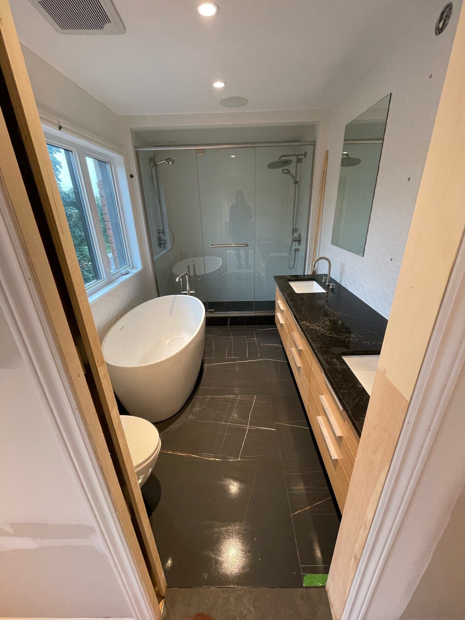 Salle de bains moderne avec baignoire îlot, douche à l'italienne, meuble-lavabo foncé et grande fenêtre