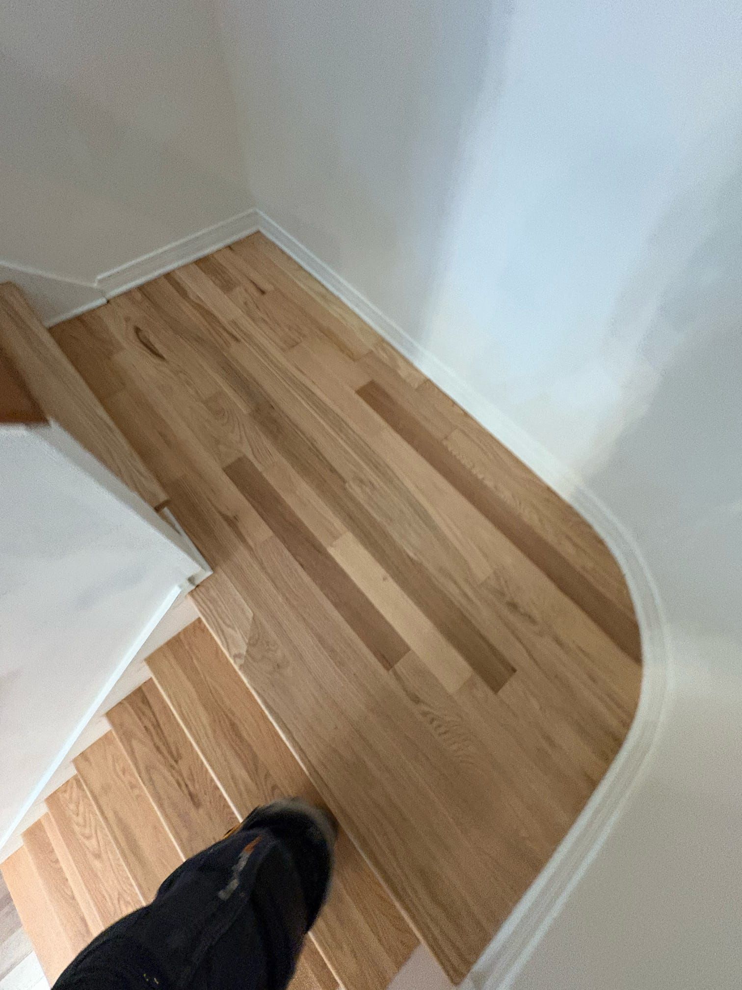 Coin de parquet avec murs blancs et une chaussure noire au bord inférieur