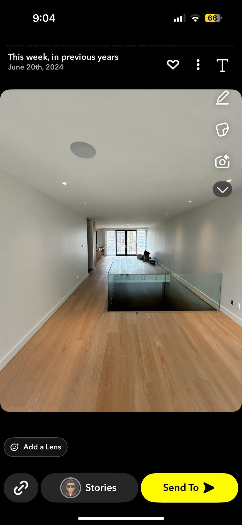 Salon moderne vide avec parquet, murs blancs et grandes fenêtres, vu du couloir.