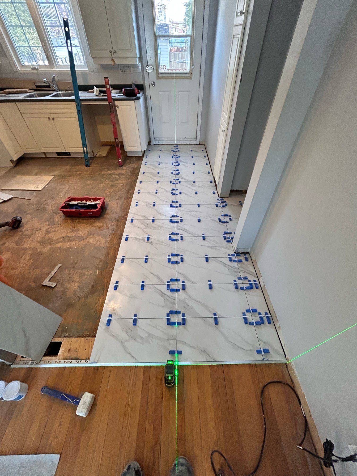 Une bâche en plastique recouvrait le sol d'un couloir pendant les travaux de rénovation, avec les outils et les matériaux à proximité.