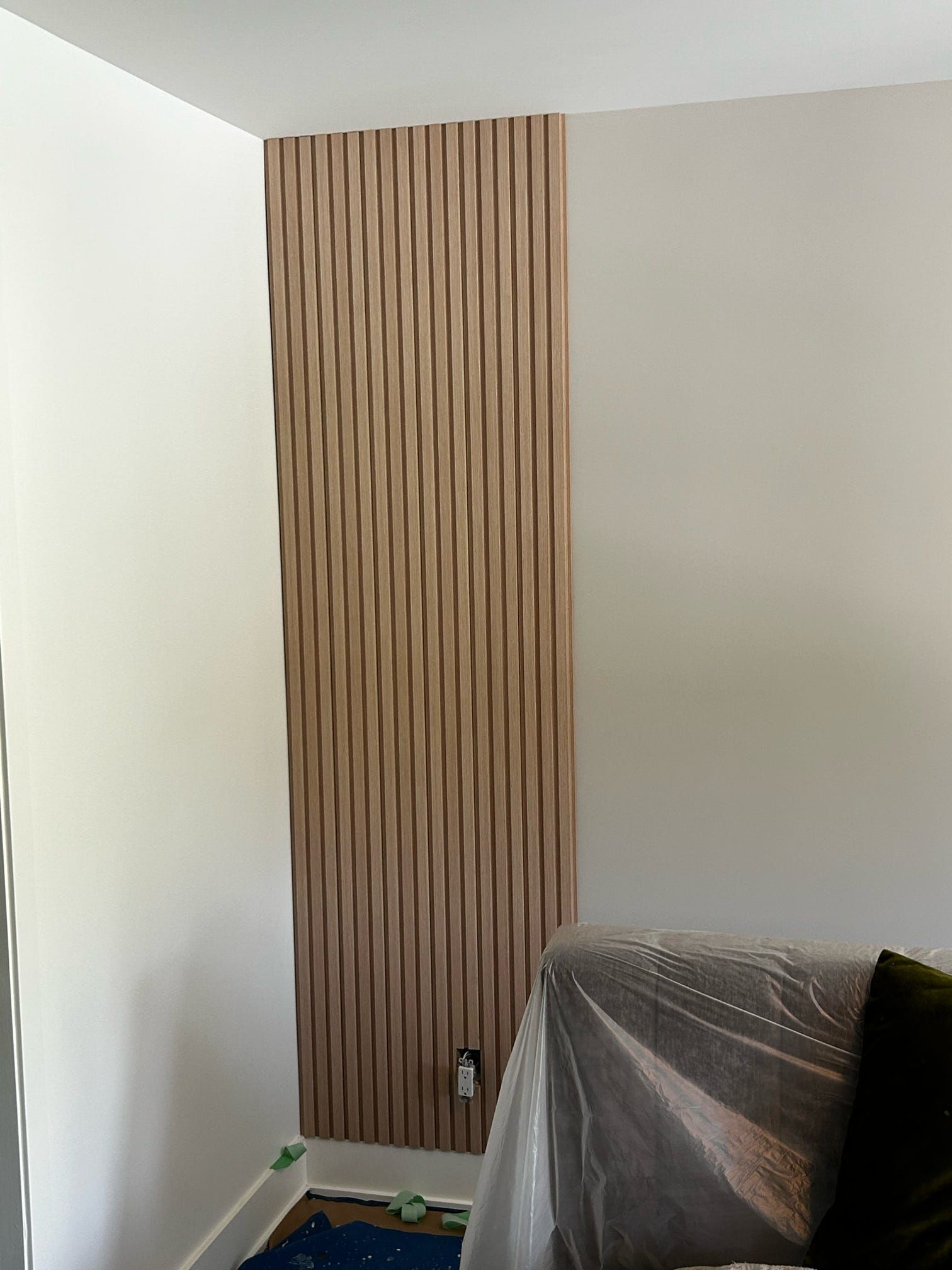 Coin de pièce vide avec un mur d'accent en lattes de bois verticales et une chaise recouverte